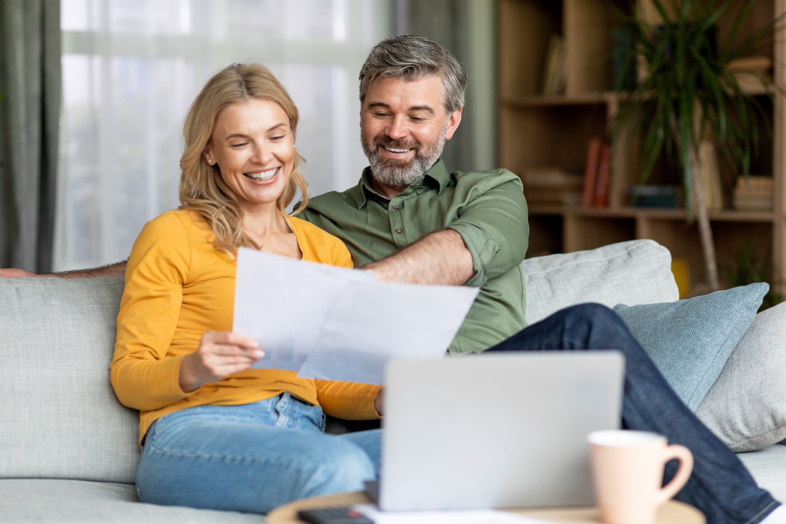 Family Insurance Concept. Happy Middle Aged Couple Reading Documents At Home Family Insurance Concept. Happy Middle Aged Couple Reading Documents At Home, Smiling Mature Spouses Checking Financial Papers While Sitting Together On Couch In Living Room, Free Space